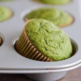 Whole grain green muffin tipped halfway in muffin tin.