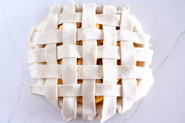 Assembling lattice pie crust on fresh peach pie.
