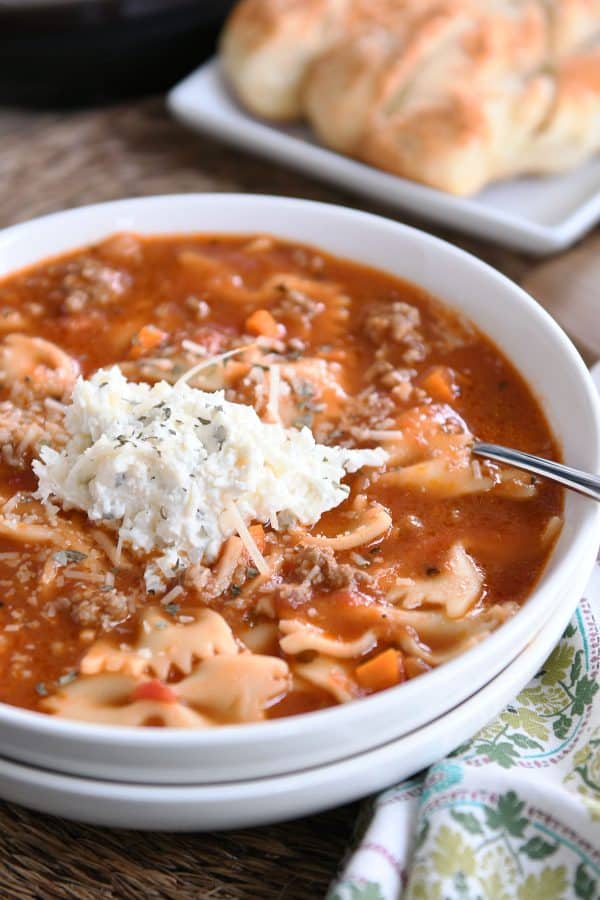 White bowl filled with pressure cooker lasagna soup and dollop of cheesy ricotta mixture. 