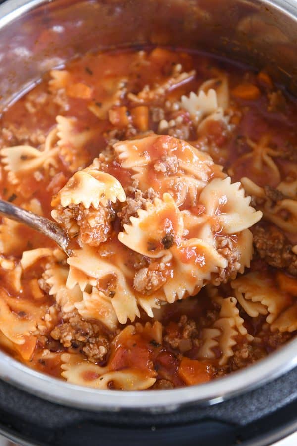 Ladle taking out a scoop of lasagna soup from pressure cooker.