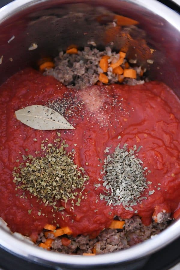 Making pressure cooker lasagna soup with crushed tomatoes and spices.