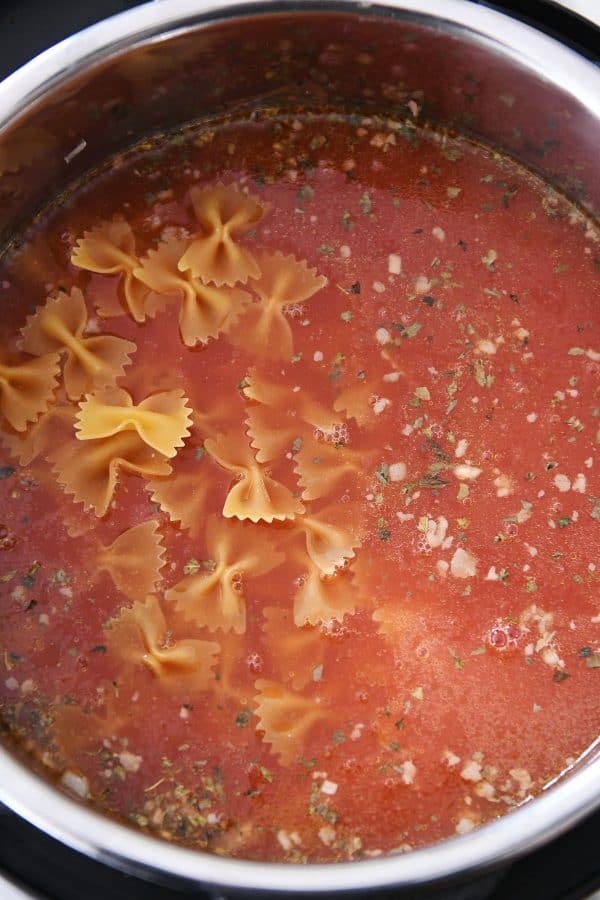 Adding pasta and broth to pressure cooker for lasagna soup.