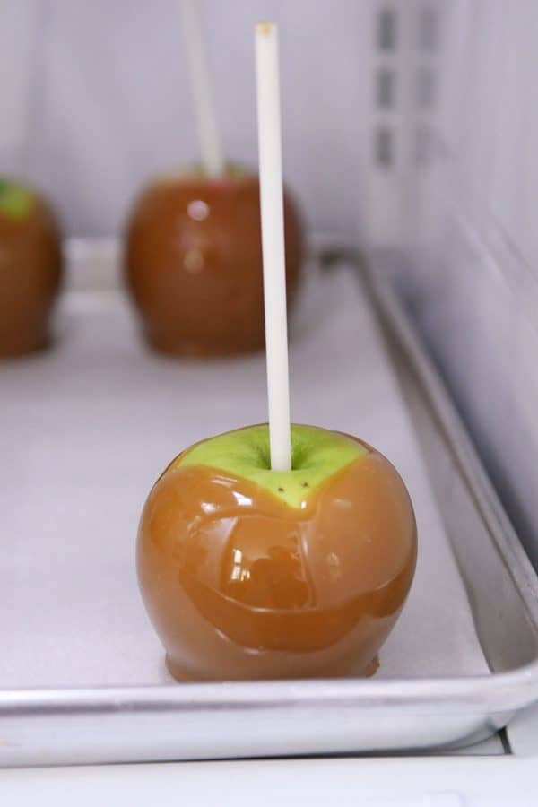 Granny Smith apple with caramel on sheet pan in refrigerator.