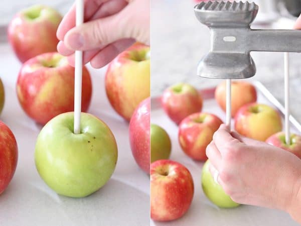 Pounding in white sticks to apples before dipping in caramel.