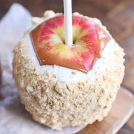 Dipped and decorated homemade caramel apple with white chocolate and graham cracker crumbs.