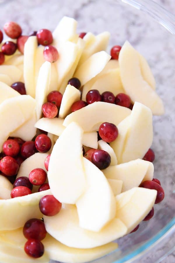 Glass bowl with sliced apples and fresh cranberries.