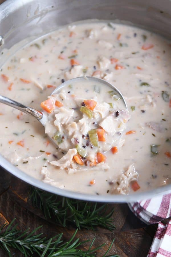 Ladle scooping out best leftover turkey soup, creamy vegetable, turkey and rice.