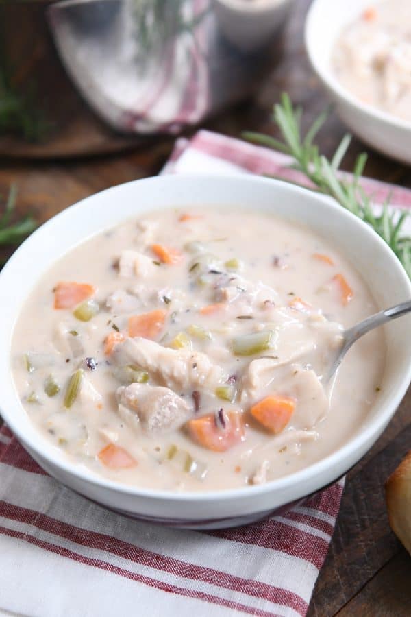 White bowl with the best leftover turkey soup, creamy vegetable, turkey and rice.