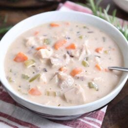 White bowl with the best leftover turkey soup, creamy vegetable, turkey and rice.