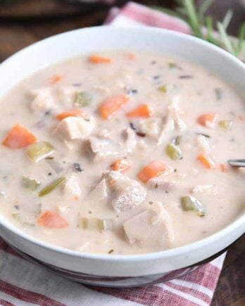 White bowl with the best leftover turkey soup, creamy vegetable, turkey and rice.