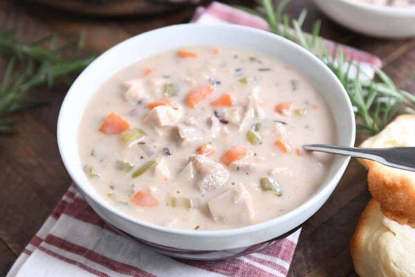 White bowl with the best leftover turkey soup, creamy vegetable, turkey and rice.