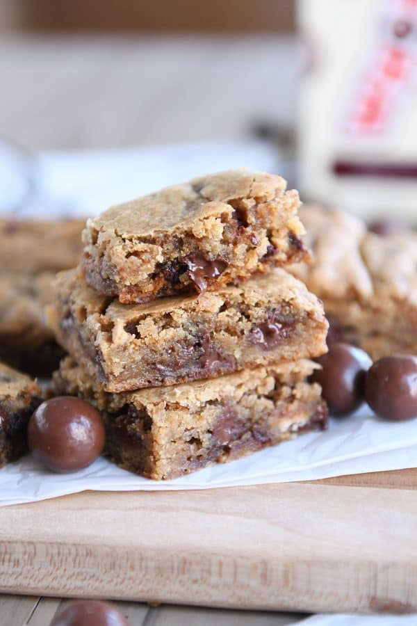 Two malted chocolate chip blondies stacked with half of a blondie on top.