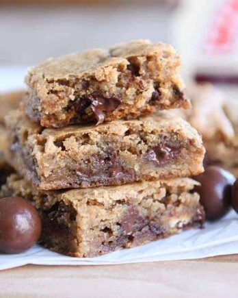 Two malted chocolate chip blondies stacked with half of a blondie on top.