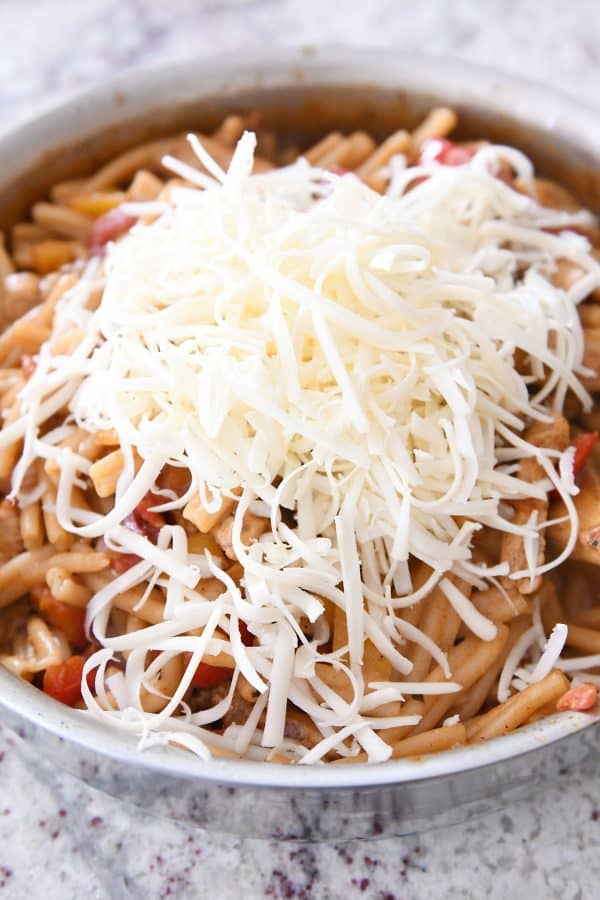 Adding cheese to skillet chicken fajita pasta.