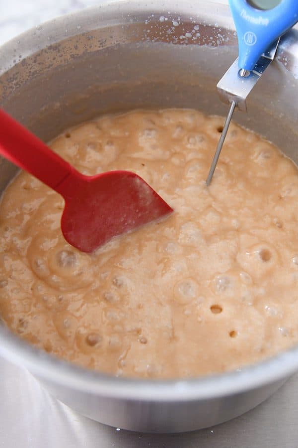 bubbling caramel being cooked and stirred with a red spatula
