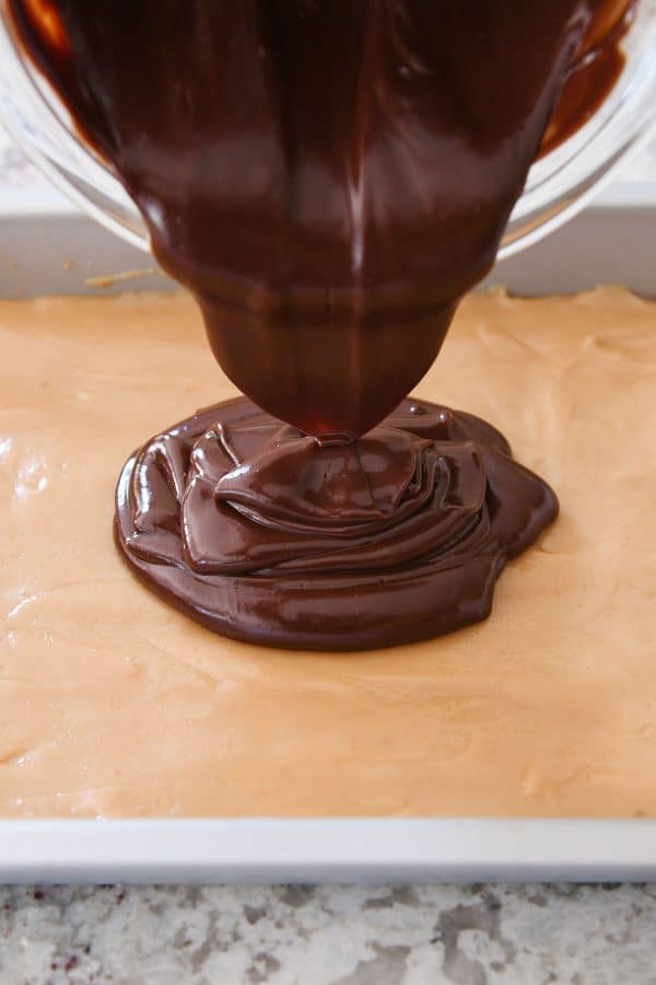 Pouring chocolate ganache on top of caramel.