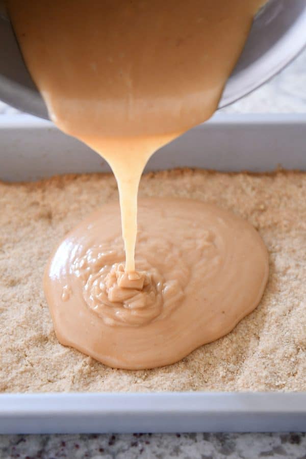 Pouring homemade caramel on top of shortbread crust.