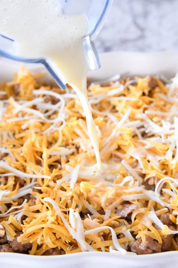 Pouring egg mixture on top of tater tot breakfast casserole.