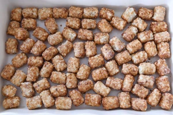 Tater tots scattered in bottom of 9X13-inch baking pan. 