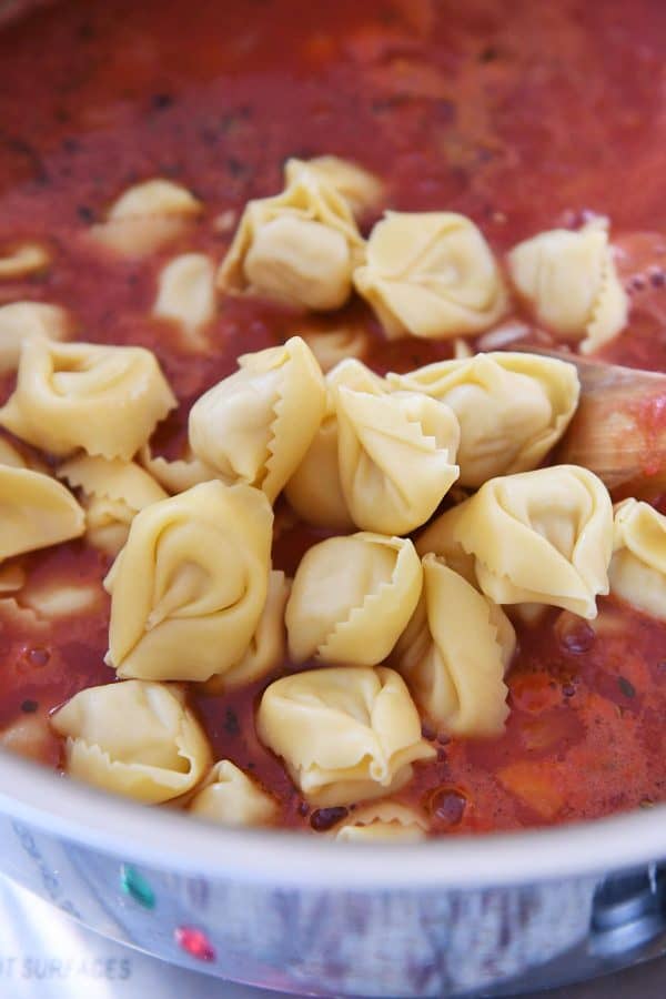 Adding the tortellini to soup.