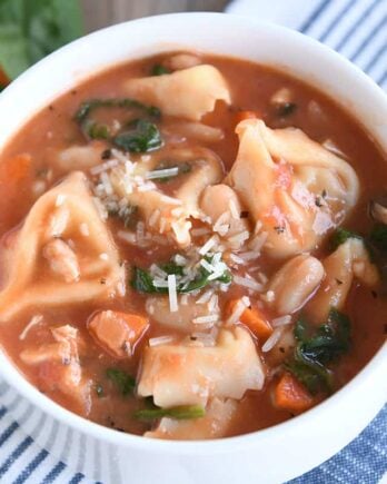 White bowl with handles filled with quick and easy creamy tuscan tortellini soup.