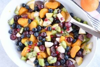 Top down view of white bowl with grapes, blueberries, pears, kiwi, oranges and pomegranate seeds for easy winter fresh fruit salad.