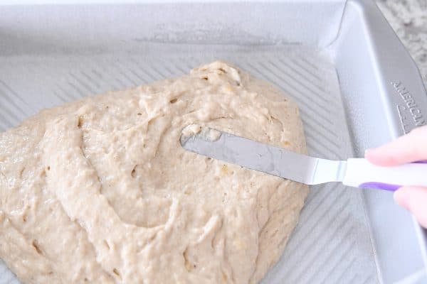 Spreading banana coffee cake batter in metal 9X13-inch pan.