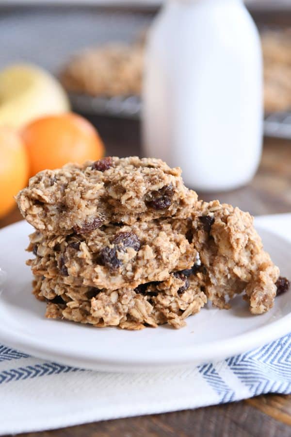 Baked oat breakfast cookies on white plate with one cookie broken in half.