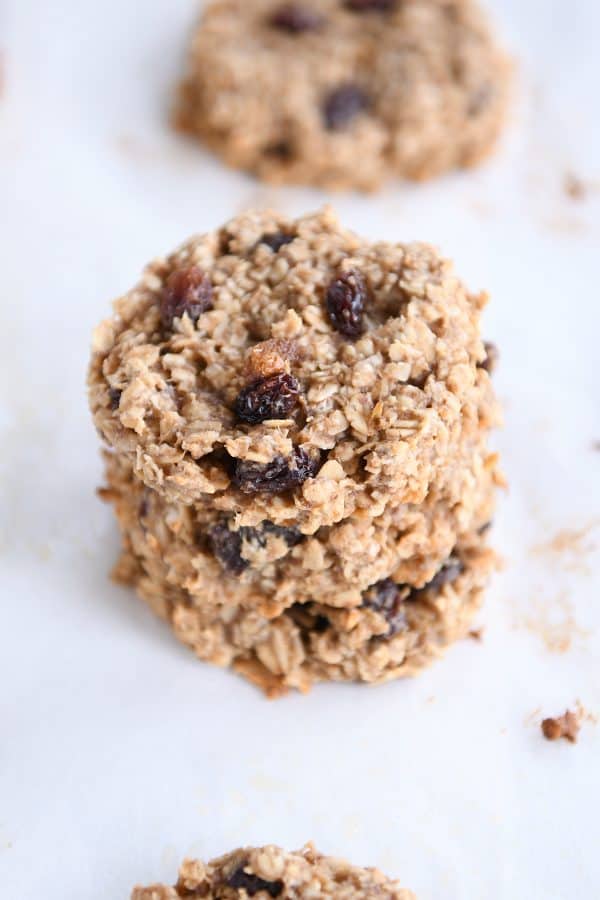 Stack of cooked oatmeal raisin breakfast cookies on a piece of parchment paper.