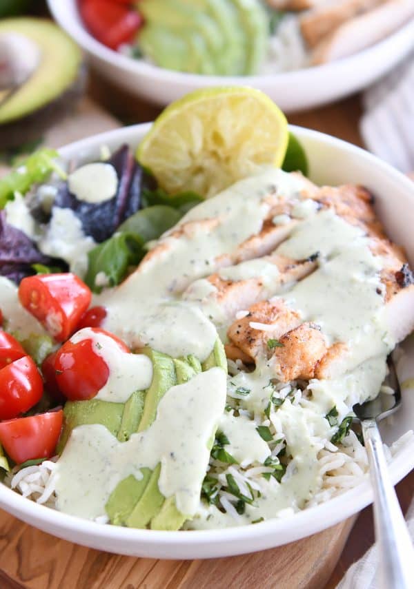 honey chipotle lime chicken bowls in white bowl with tomatoes, avocado lime dressing, and tomatoes