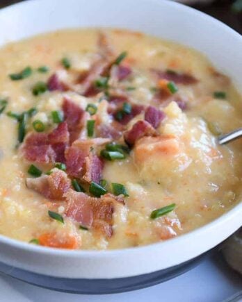 spoon in white bowl filled with cheesy cauliflower soup