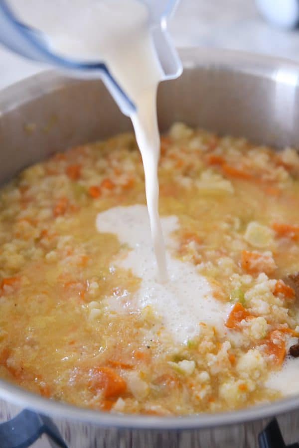 pouring milk and flour mixture into cheesy cauliflower soup