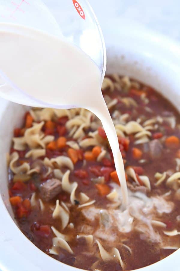 adding cornstarch slurry to slow cooker for beef vegetable noodle soup