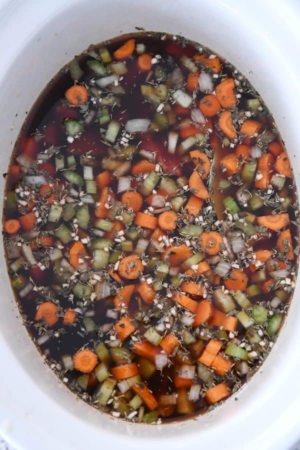 Top down view of beef broth added to slow cooker for beef noodle soup.