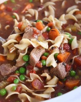 white slow cooker filled with beef vegetable noodle soup
