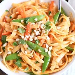 twirling instant pot red coconut curry noodles with fork in white bowl