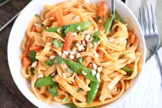 twirling instant pot red coconut curry noodles with fork in white bowl