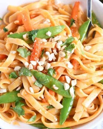 twirling instant pot red coconut curry noodles with fork in white bowl