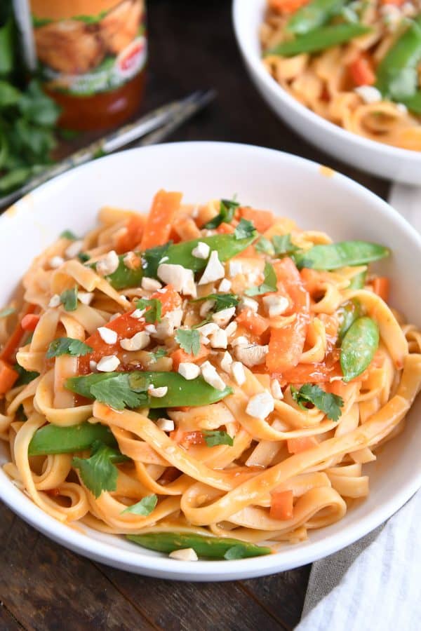 Instant Pot red coconut curry noodles in white bowl with chopped peanuts.