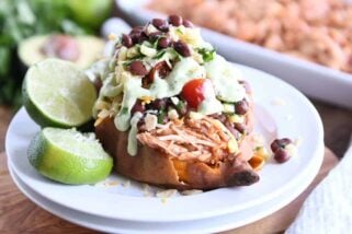 Loaded stuffed bbq chicken sweet potato with cilantro lime dressing on white plate