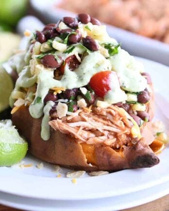 Loaded stuffed bbq chicken sweet potato with cilantro lime dressing on white plate