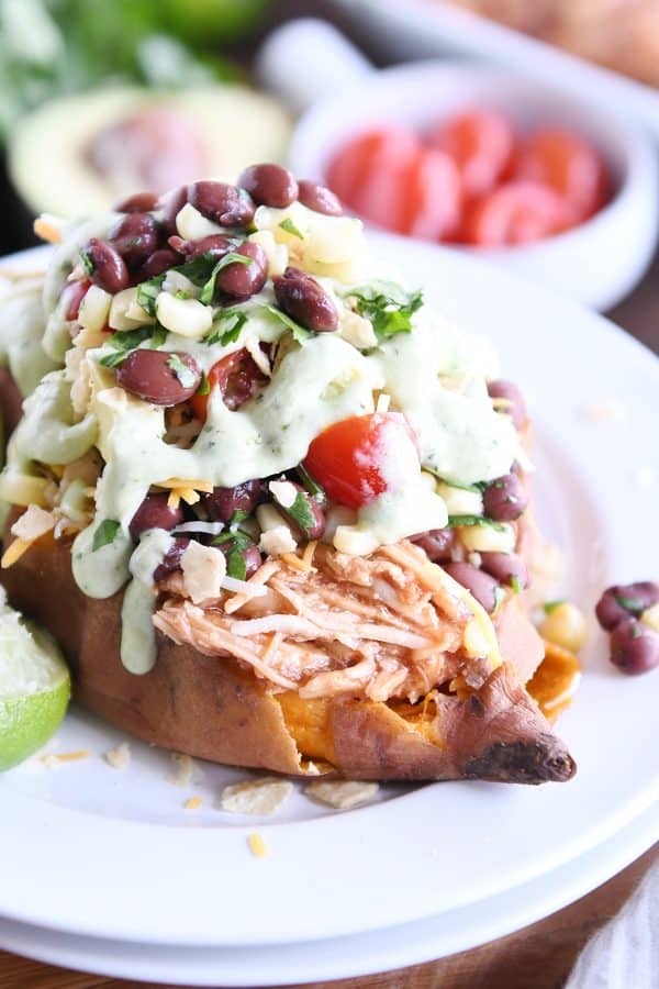 Loaded stuffed bbq chicken sweet potato with cilantro lime dressing on white plate