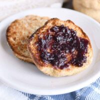 split open easy homemade english muffin with butter and jam on white plate