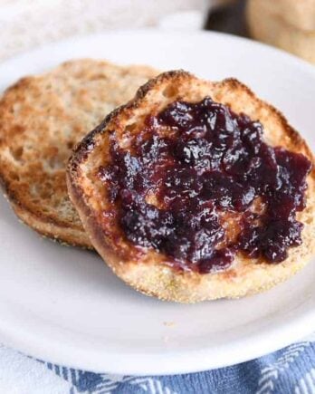 split open easy homemade english muffin with butter and jam on white plate