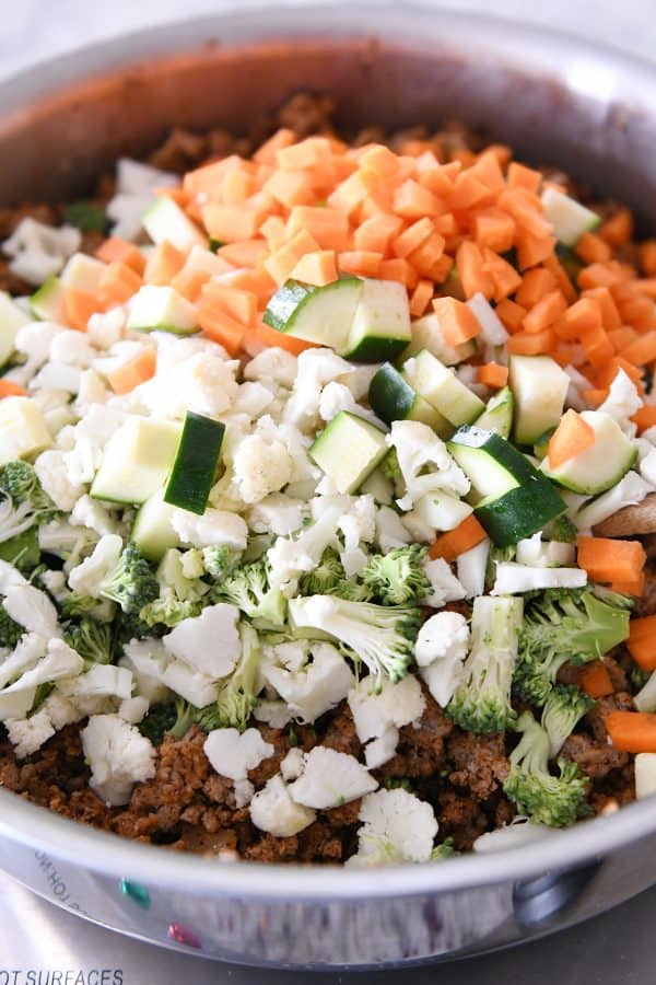 Adding vegetables to taco filling.