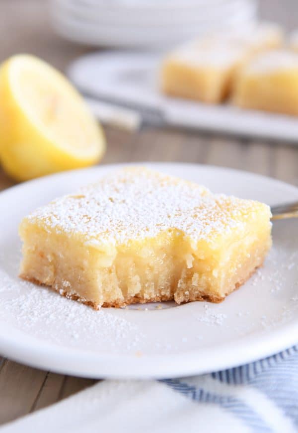 bite taken out of lemon bar white chocolate brownie on white plate