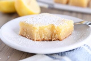 bite taken out of lemon bar white chocolate brownie on white plate