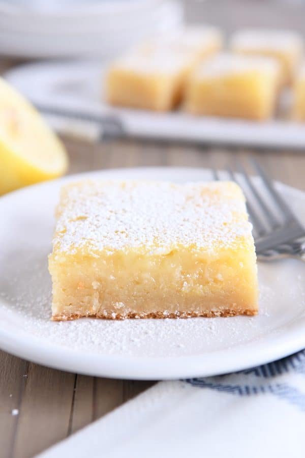 Lemon bar white chocolate brownie square on white plate.