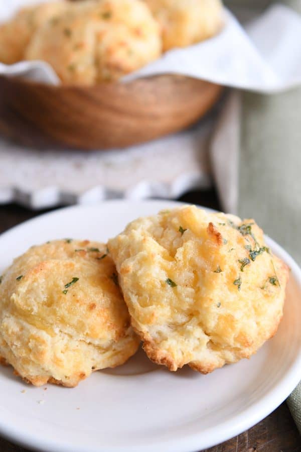 Two cheesy garlic drop biscuits on white plate.