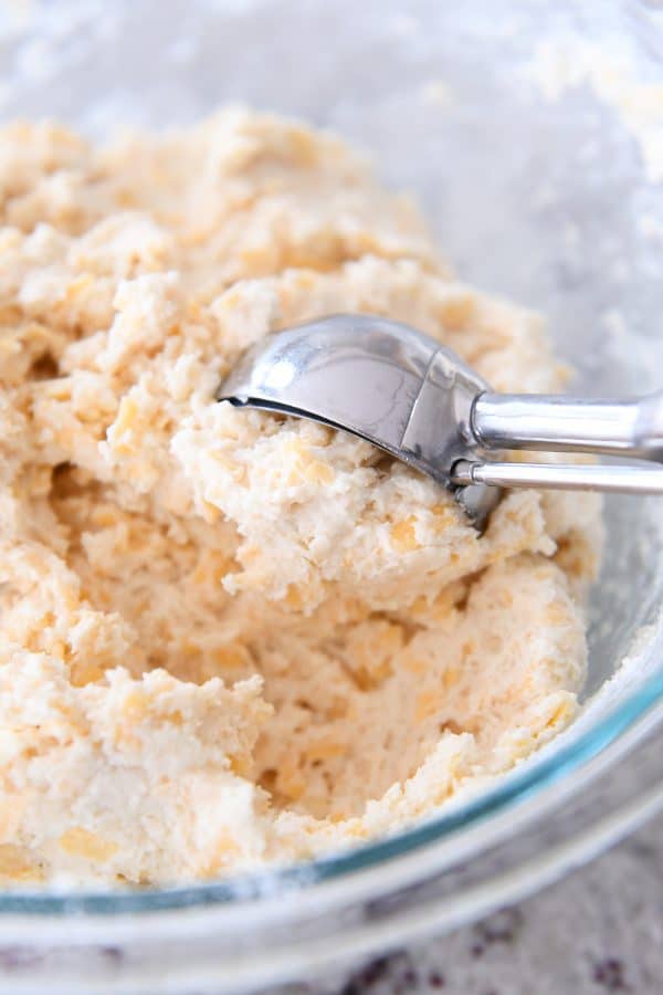 Scooping out batter for cheesy garlic drop bicuits with cookie scoop.